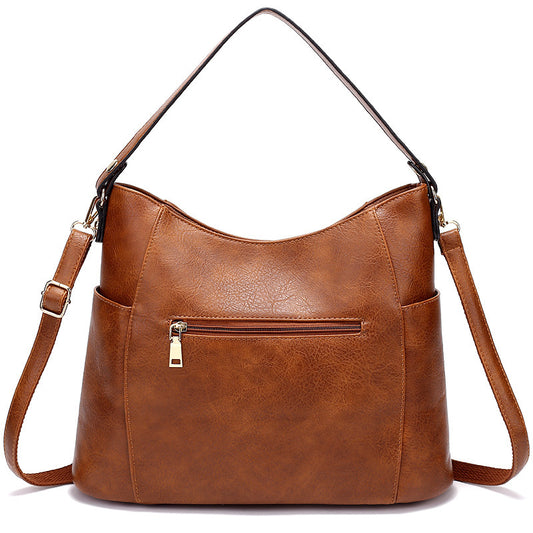Brown leather handbag with a shoulder strap on a white background