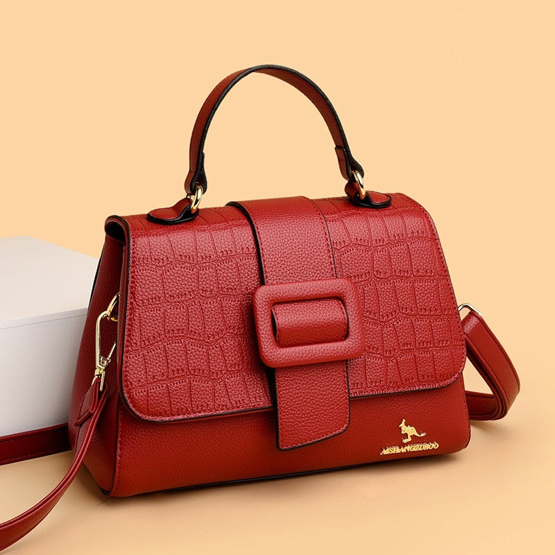 Red textured handbag with a prominent buckle on a beige background