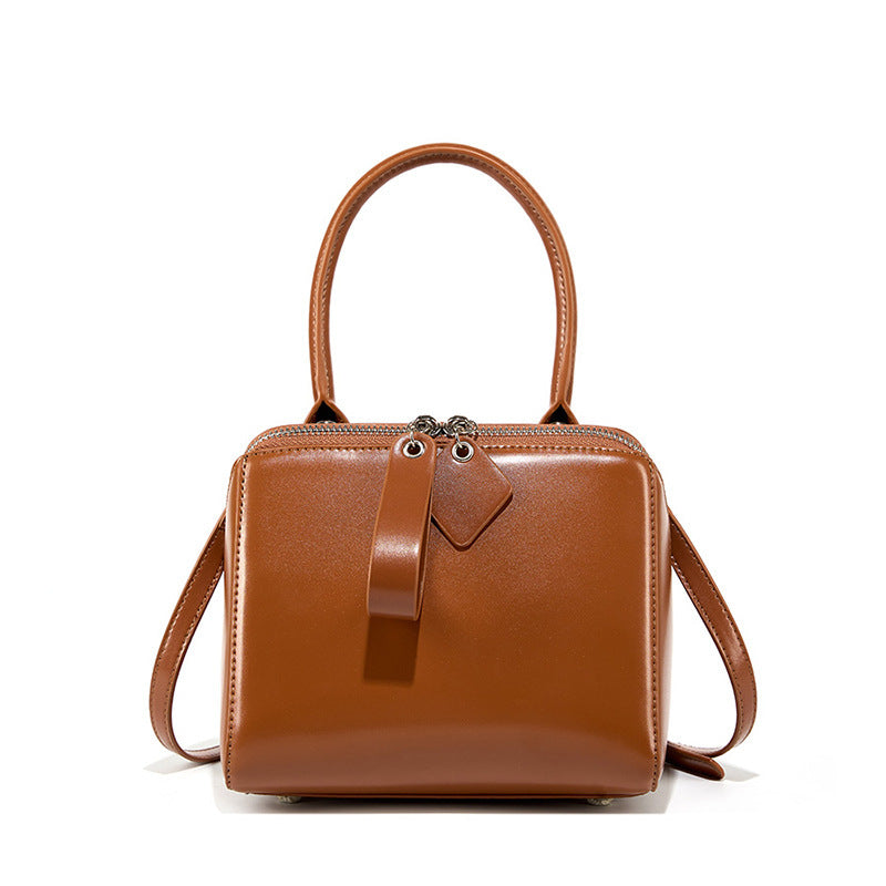 Brown leather handbag with a strap on a white background