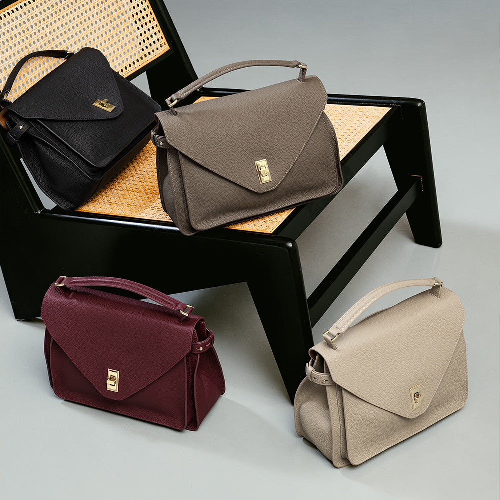 Four handbags in black, brown, red, and beige on a chair and surface.
