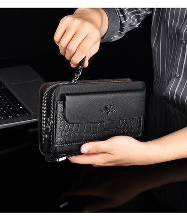 Person holding a black wallet with a visible brand logo, laptop in the background