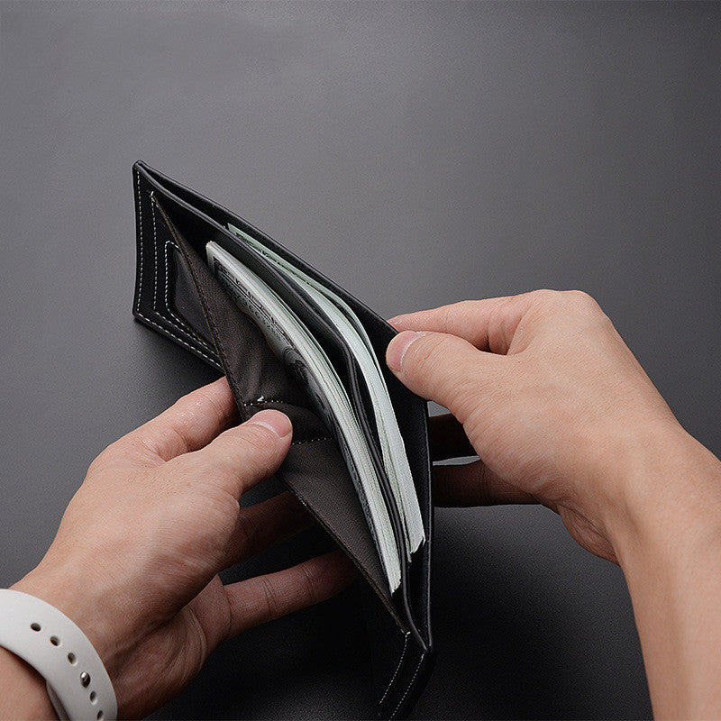Person opening a black wallet on a dark gray background