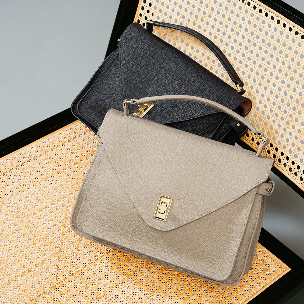 Two handbags, one black and one beige with a gold clasp, on a textured surface.