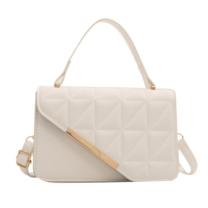 White quilted handbag with gold accents on a white background
